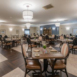 An elegant dining room with neatly arranged tables and chairs, featuring chandeliers and a sophisticated ambiance.