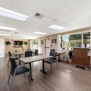 A bright and welcoming multipurpose room with tables, chairs, and large windows.