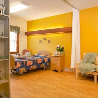 A bright and welcoming hospital room with a bed and sitting area.