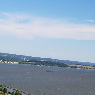 A serene view of a river with boats gliding under a clear blue sky.