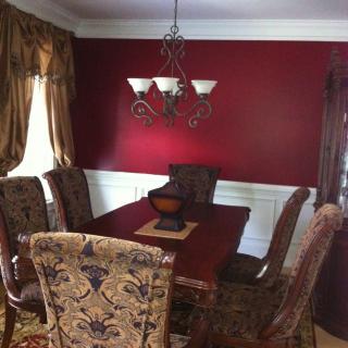 A traditionally decorated dining room with red walls, ornate chairs, and a chandelier.
