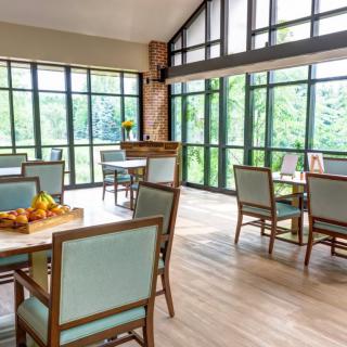 A bright and airy dining area featuring modern furniture and large windows allowing natural light to flood the space.