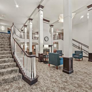 Elegant lobby with carpeted stairs, columns, and seating area.