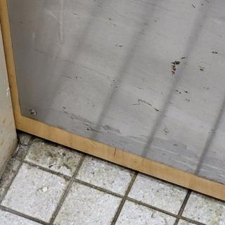 A window frame with a screen sits above a tiled floor.
