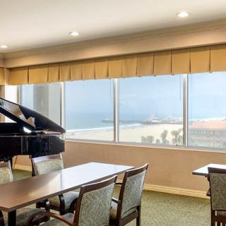 A meeting room with a grand piano and large windows overlooking the ocean.