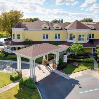 A charming yellow building with a covered entrance and landscaped surroundings under a blue sky.