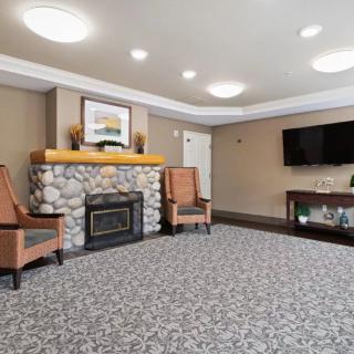 A cozy living room with a stone fireplace, comfortable seating, a large television, and decorative elements including a painting above the mantel.