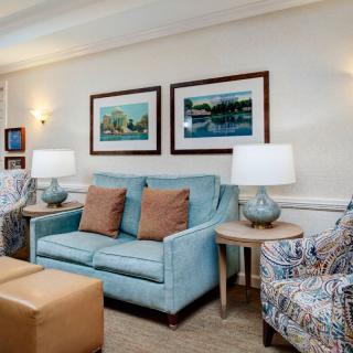 A cozy living room with a blue sofa, patterned armchair, and complementary decor.