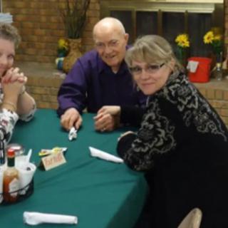A group of people seated around a table indoors, engaging in a social gathering.