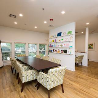 A modern conference room with a long table, comfortable chairs, and an art display on the wall.