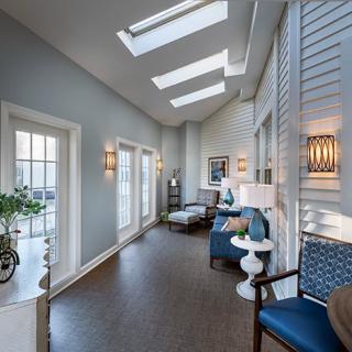 A modern interior with skylights and a cozy seating area, featuring blue chairs and ample natural light.