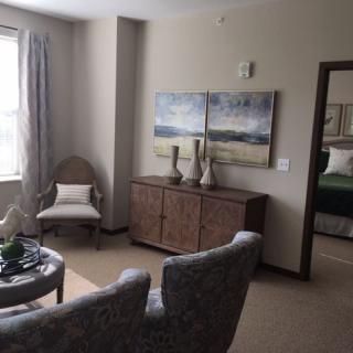 A cozy living room featuring elegant furniture and artwork, with natural light streaming through a window.
