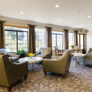 A cozy seating area with plush chairs, tables, and large windows.