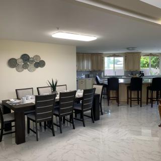 A modern dining area with a table and chairs, adjacent to an open kitchen with bar stools.