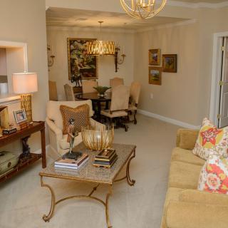 A cozy living room with elegant furniture and decor, featuring a sofa, coffee table, and chandelier.