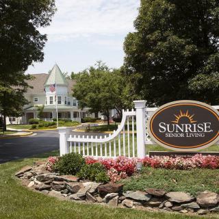 Entrance to a residential or commercial property with well-maintained landscaping and a visible sign.