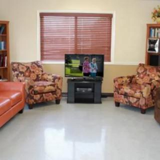 Cozy living room with a mix of floral armchairs and a leather couch, centered around a television.