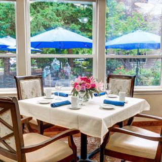 A cozy dining area with a neatly set table near large windows offering a view of blue outdoor umbrellas.