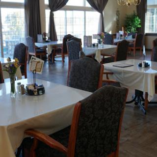 A beautifully arranged dining area with elegant tables and chairs, featuring natural light from large windows.