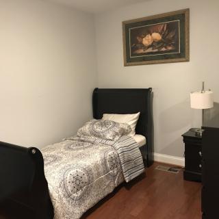A cozy bedroom with a single bed, nightstand, and a decorative painting on the wall.