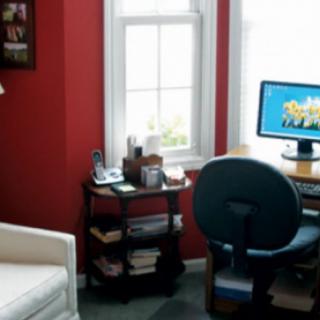 A cozy home office setup with a computer desk, chair, and window.
