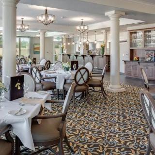 An elegant restaurant dining area with neatly arranged tables and chairs, featuring a stylish carpet and refined decor.