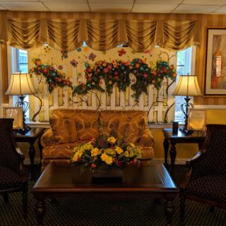 A cozy living room space featuring a floral backdrop, a comfortable sofa, and decorative lamps.