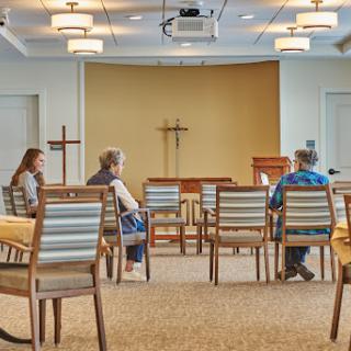 A serene meeting room set up for a gathering with chairs arranged facing a podium.
