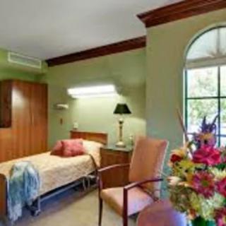 A cozy room with a bed, chair, and decorative flowers by the window.