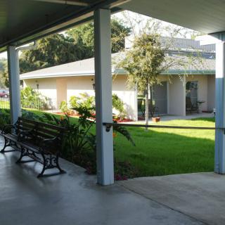 A tranquil outdoor walkway with benches, surrounded by greenery and modern architecture.