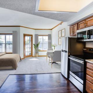 A modern open-plan apartment featuring a kitchen and bedroom area with ample natural light.