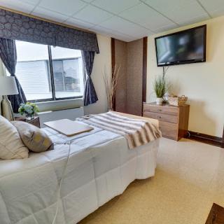 A cozy and modern bedroom featuring a comfortable bed, a television, and natural light from the window.