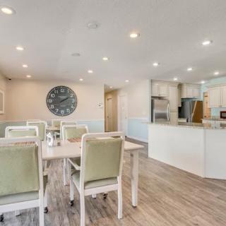 A modern open-concept kitchen and dining area with white furniture and wood flooring.