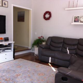 A cozy living room with a gray sofa, television, and decorative elements on the shelves.