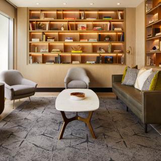 A cozy living room with modern furniture, featuring a large bookshelf and comfortable seating.