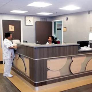 Two people interacting at a reception desk in a medical office.