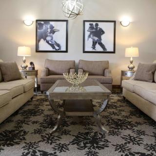 A well-decorated living room with neutral-toned sofas, a patterned rug, and contemporary artwork.