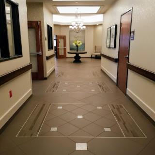 A well-lit, elegantly designed hallway featuring art on the walls and a flower arrangement in the center.