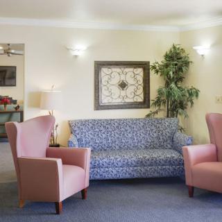 A cozy living room with a patterned sofa, pink armchairs, and decorative wall art.