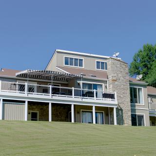 A modern house with a stone facade and large windows, set against a clear blue sky.