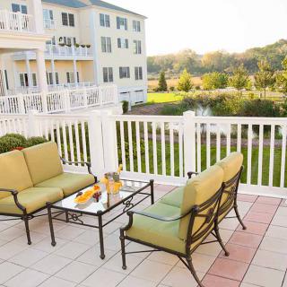 A cozy patio with outdoor seating overlooking a scenic landscape and apartment building.