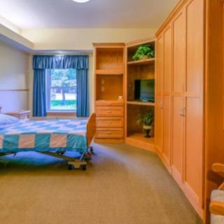 A cozy bedroom with a colorful quilt on the bed and a wooden wardrobe.