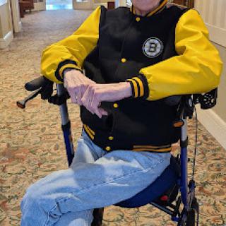 A senior individual in a black and yellow jacket seated in a wheelchair, enjoying the indoor environment.