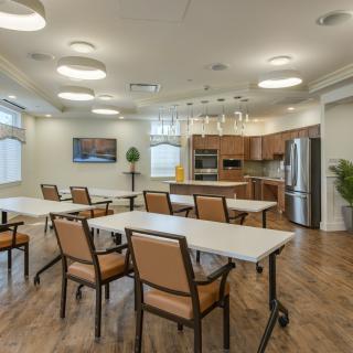 A modern kitchen and dining area with tables, chairs, and wooden flooring.