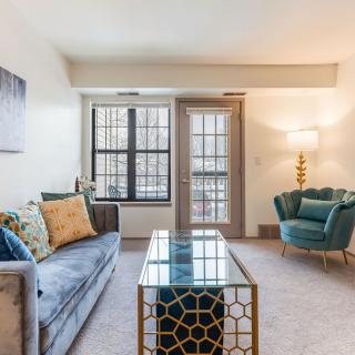 A stylish living room with modern furniture, featuring a comfortable sofa, a unique coffee table, and an elegant armchair next to a floor lamp.