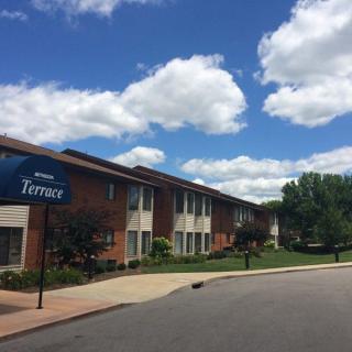 A sunny day view of a residential apartment complex with a clear blue sky and fluffy clouds.