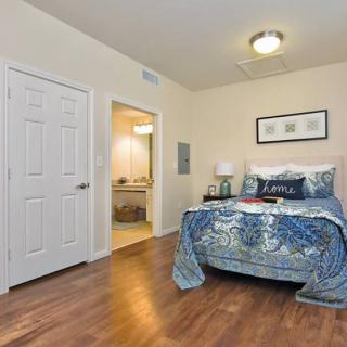 A cozy bedroom with modern decor, featuring a comfortable bed adorned with blue bedding and a nightstand holding a lamp.