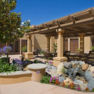 A beautifully landscaped courtyard featuring a pergola with outdoor seating and vibrant garden plants.
