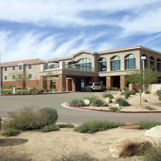 A modern building surrounded by desert landscaping under a blue sky.