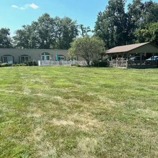 A serene outdoor space featuring a well-maintained lawn and buildings under a clear blue sky.